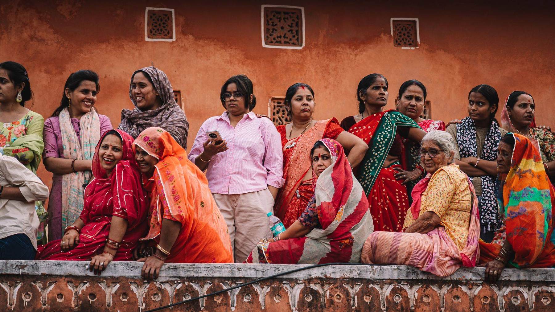 Gruppe indischer Frauen in Saris vor ockerfarbener Wand