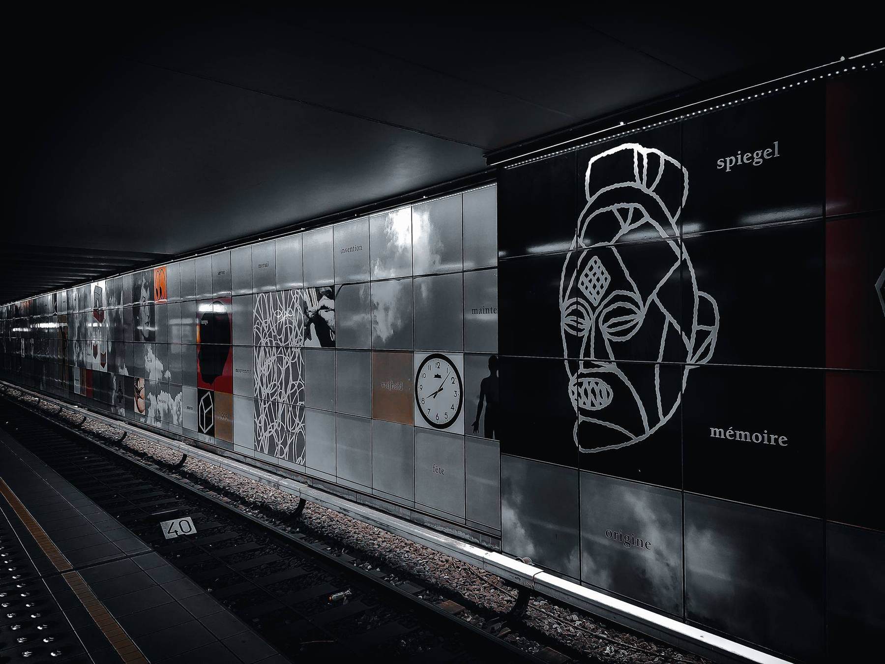 U-Bahnhof mit Wandkunst und Maskenmotiv in Schwarz-Weiß