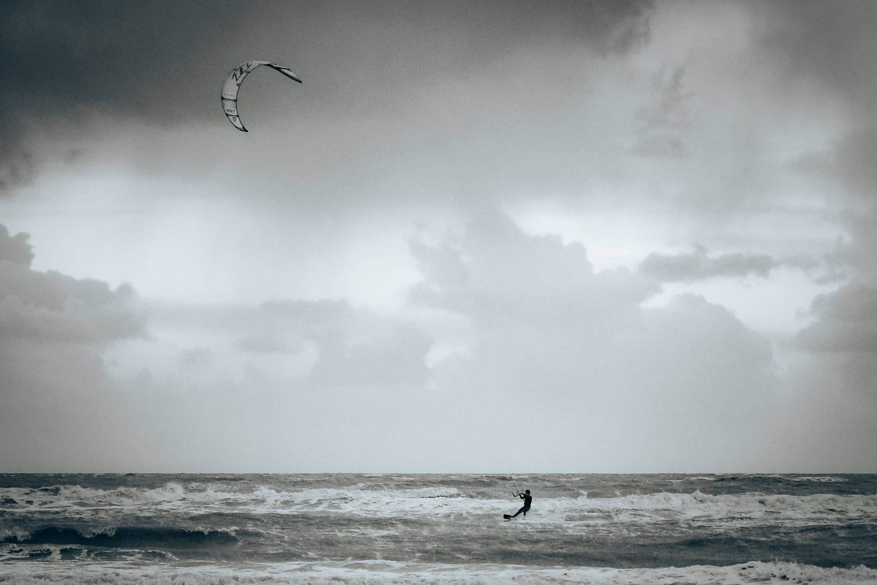 Kitesurfer unter stürmischem Himmel auf offener See