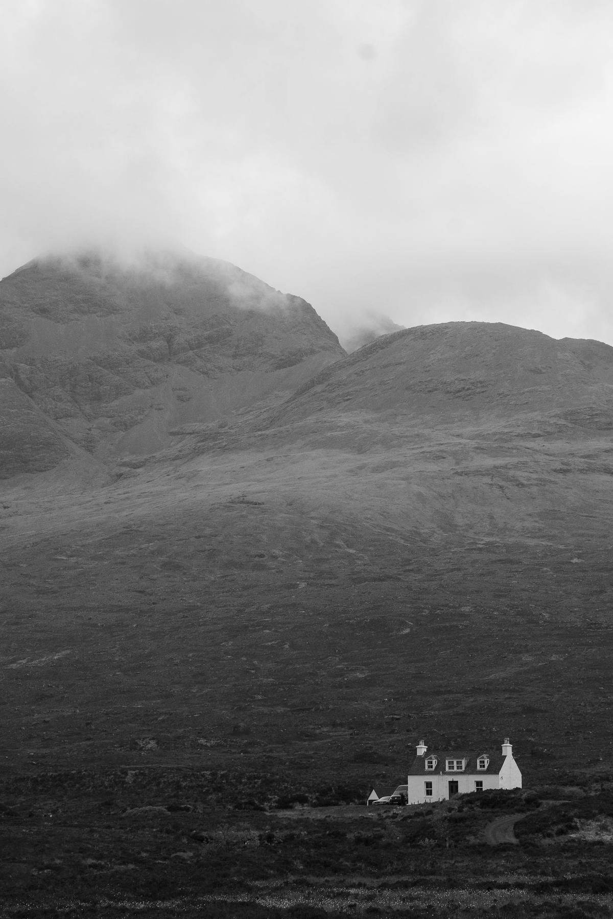 Weißes Cottage unter nebelverhangenen Bergen auf Skye