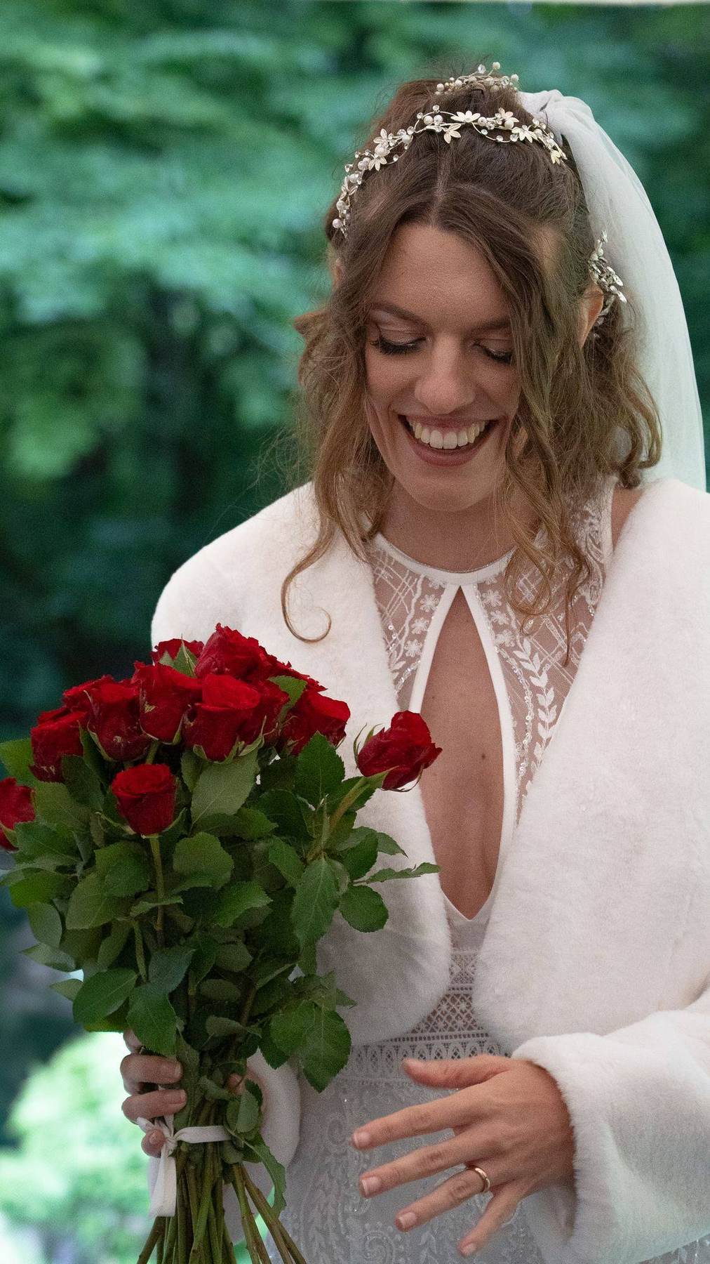 Laura lächelt auf ihren Rosenstrauß hinab