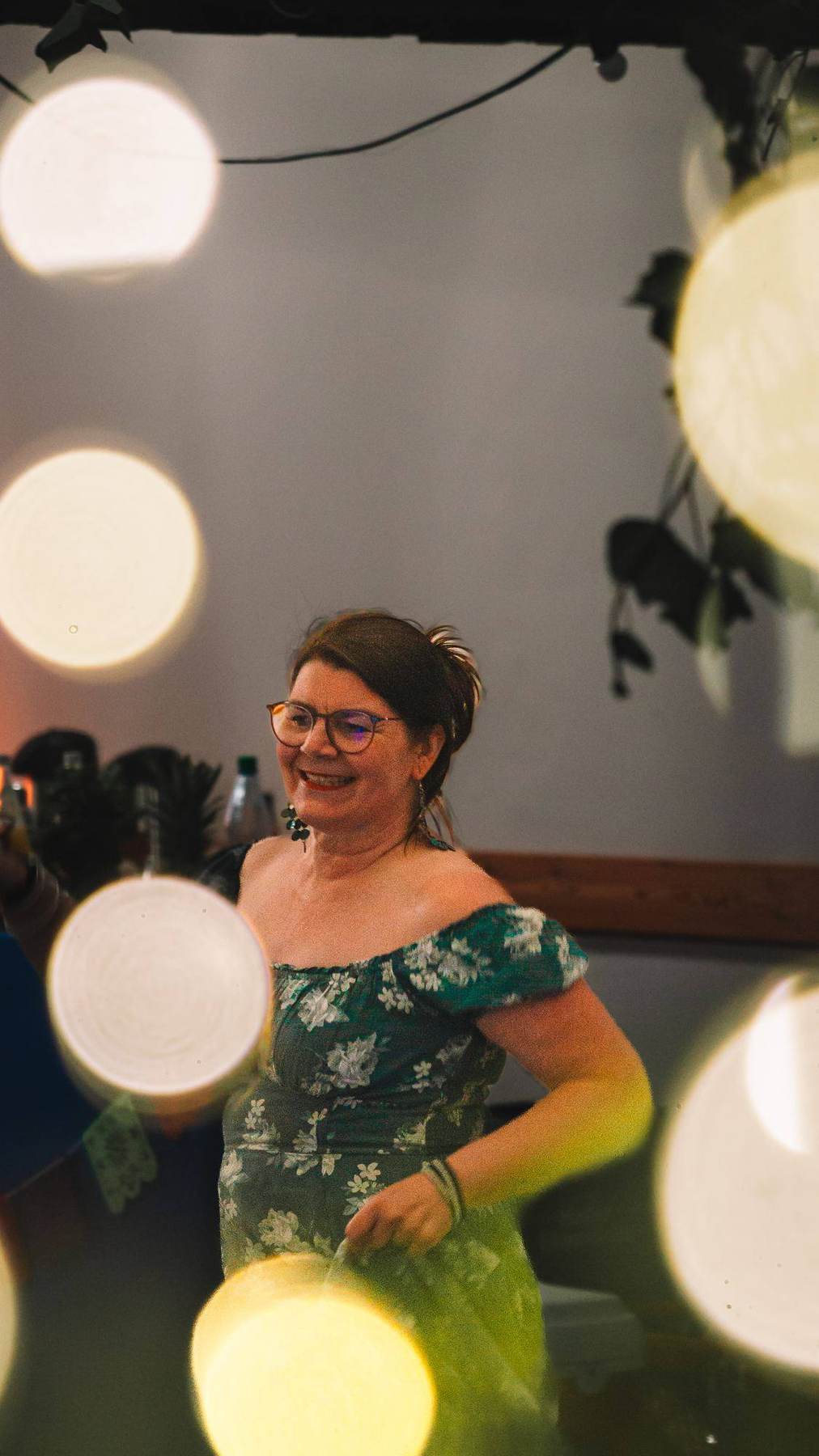 Gast in geblümtem Kleid unter Lichterketten