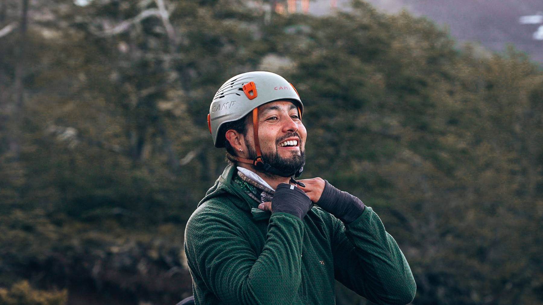 Ein Bergsteiger schnallt lachend seinen Helm fest