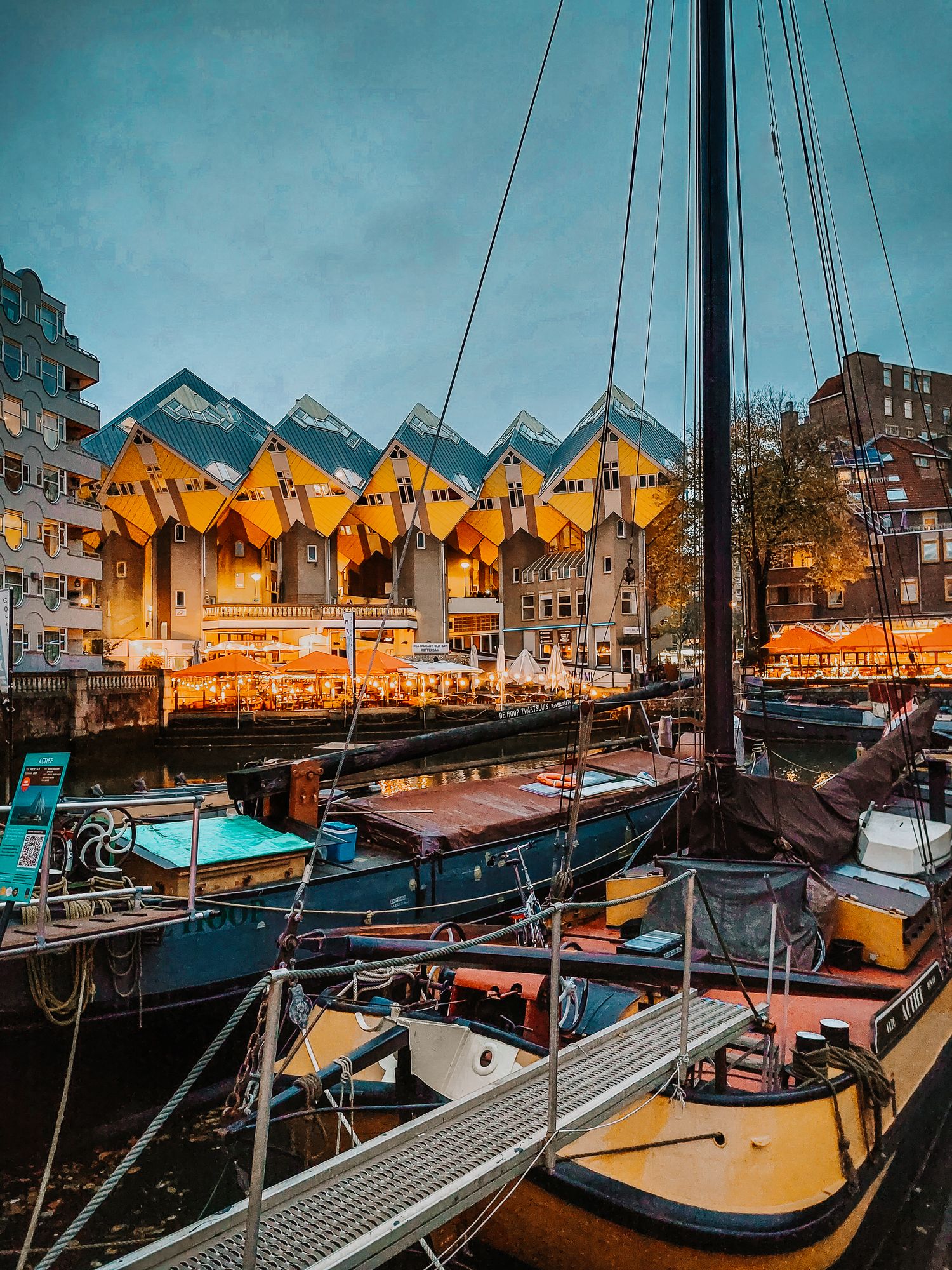 Kubuswoningen in Rotterdam mit Hausbooten im Vordergrund zur blauen Stunde