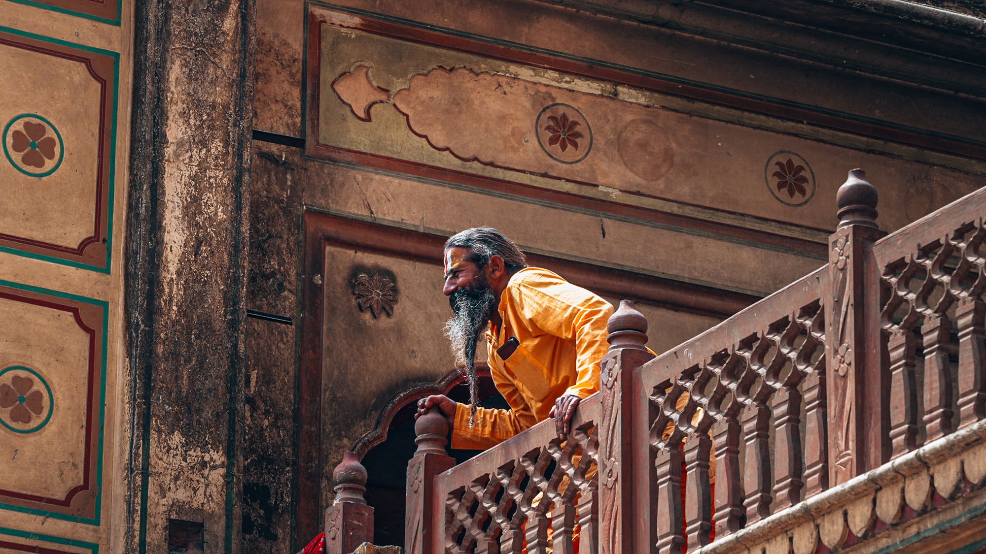 Sadhu mit langem Bart auf einem Balkon in Varanasi, Indien