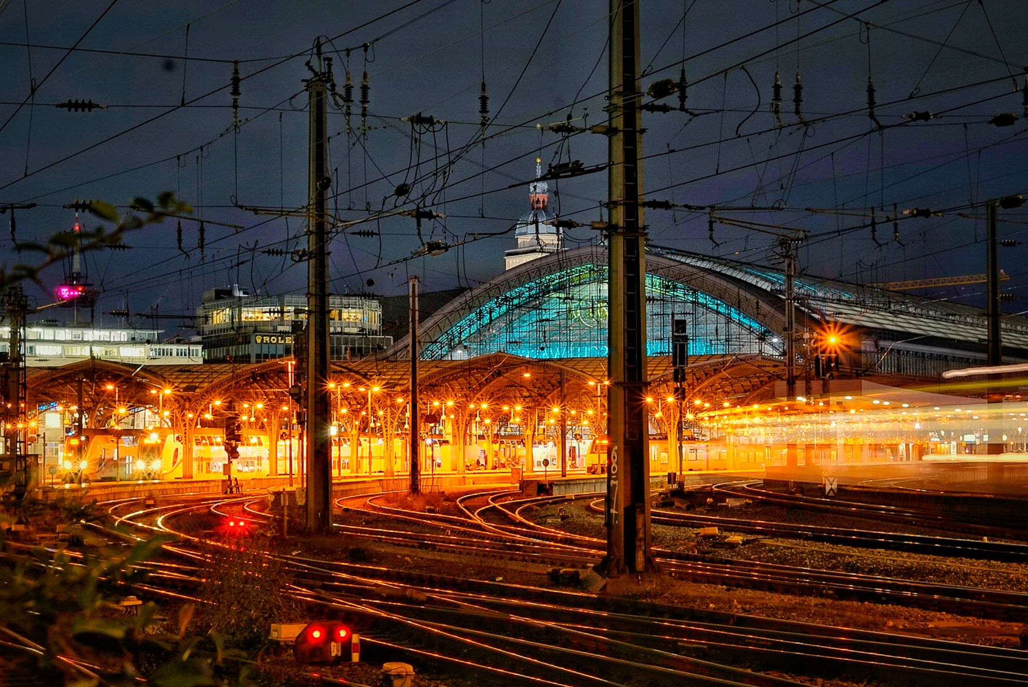 Hauptbahnhof bei Nacht mit beleuchteter Glaskuppel über den Gleisen
