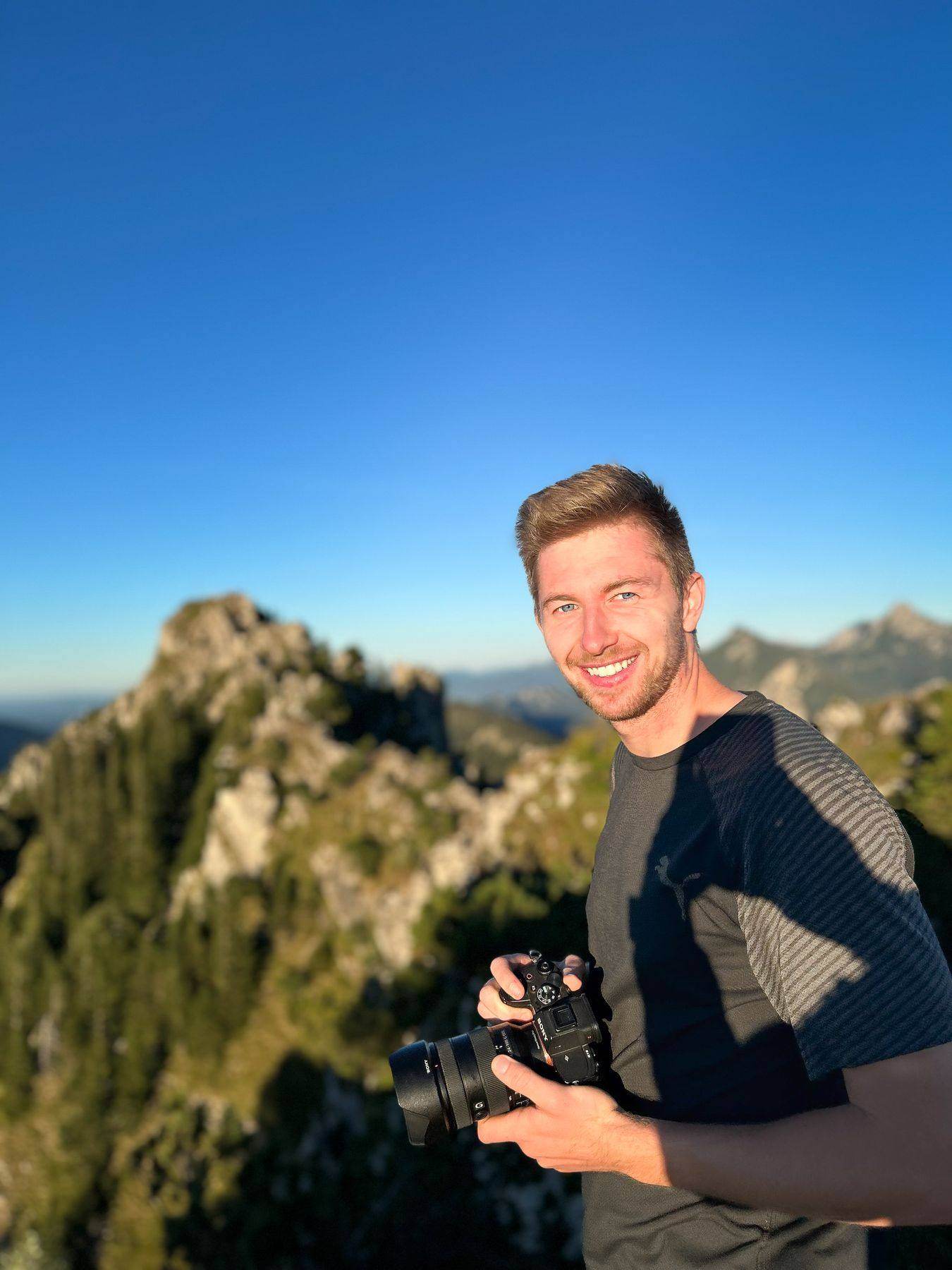 Robin Brunner mit Kamera auf einem Bergrücken